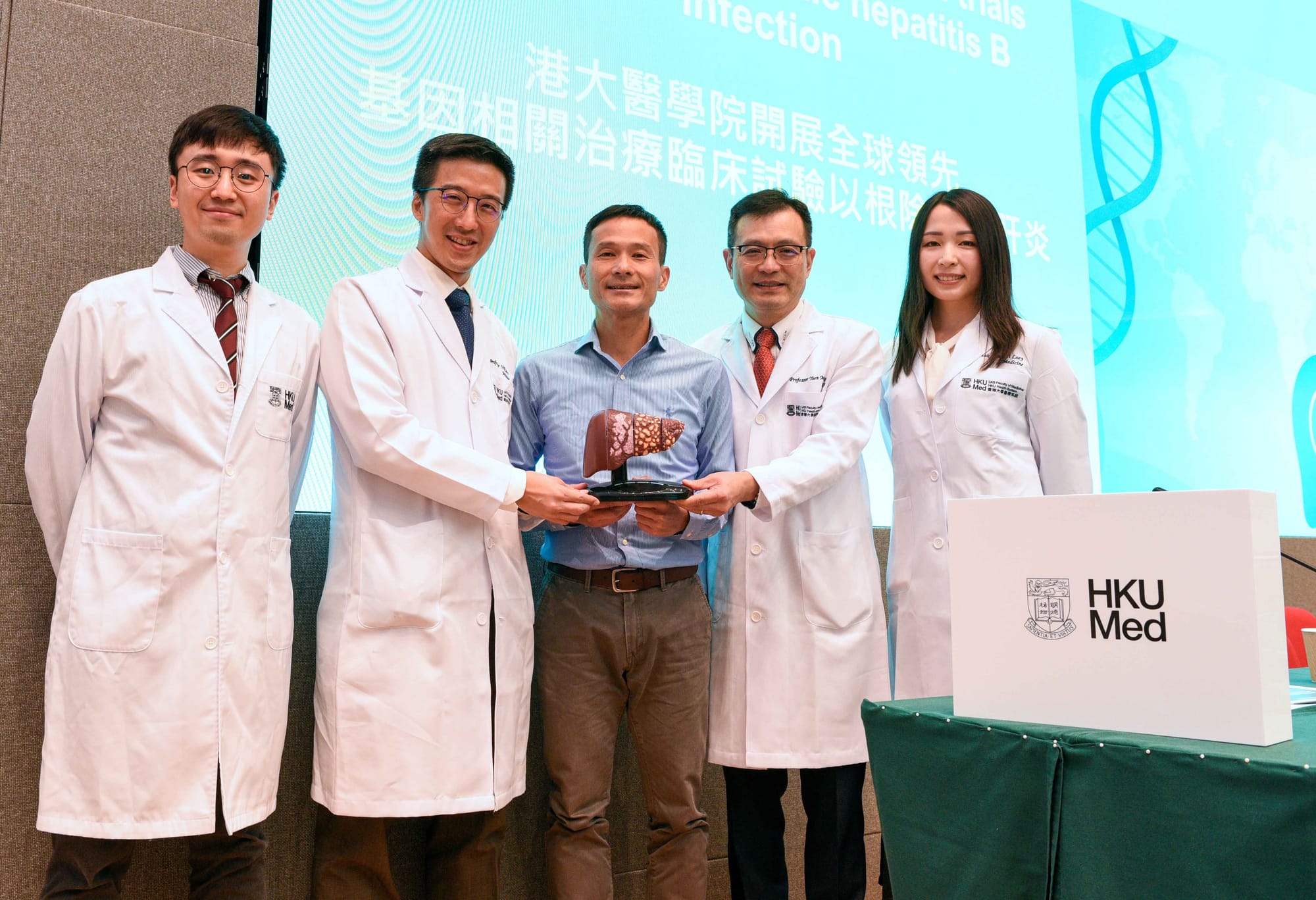 港大醫學院腸胃肝臟科研究團隊正在開展針對乙肝的創新基因相關療法,有望讓患者擺脫長期服藥的困擾,帶來新契機。研究團隊成員包括(穿白袍者右起):麥龍兒醫生、袁孟峰教授、司徒偉基教授和許允軒醫生,以及參與測試並已完成用藥的病人張先生(中)。(資料來源:香港大學新聞稿)