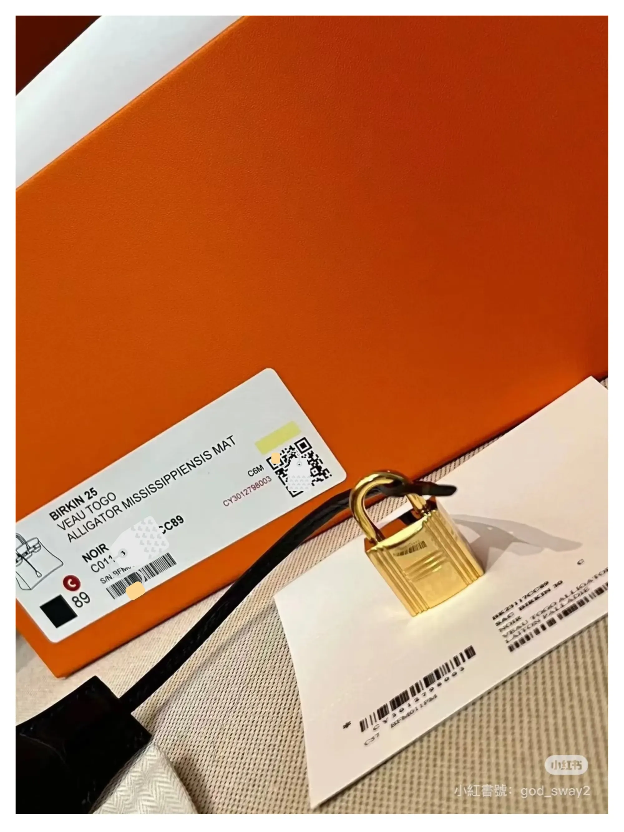 Hermès&nbsp;橙色盒外產品標籤示例，顯示&nbsp;Birkin 25、皮質（Alligator Mississippiensis Mat）、顏色&nbsp;Noir（#80）、序號及&nbsp;QR Code&nbsp;等資訊。